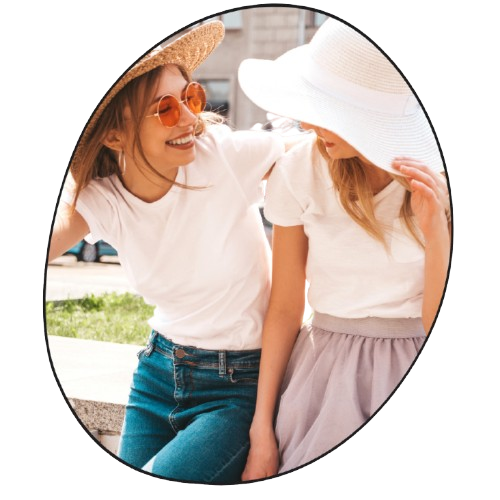 Two women sitting outdoors wearing white tops and hats, one with sunglasses.

