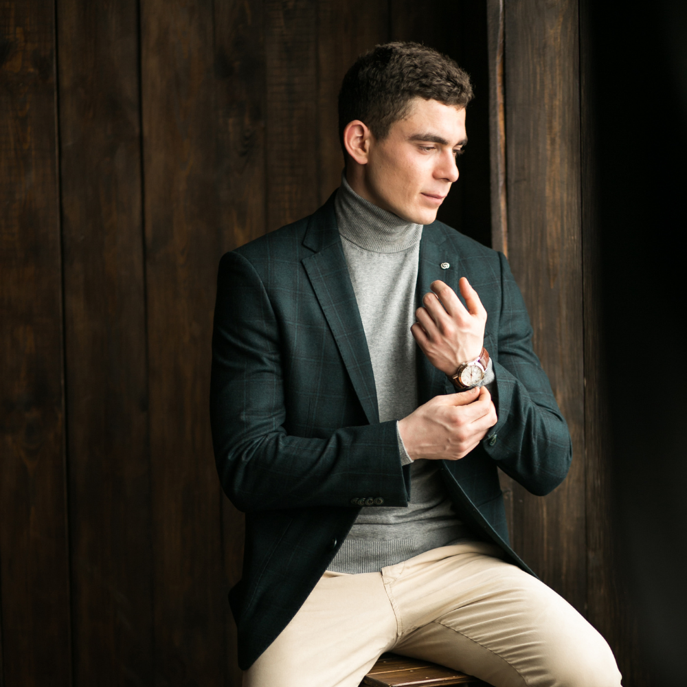 Man adjusting his jacket against a wooden background

